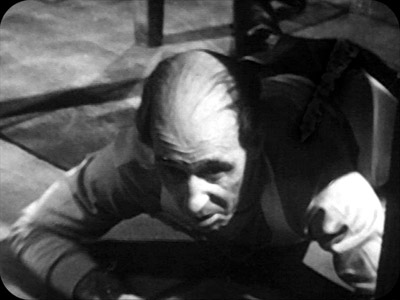 Griff the Chef hides under the table during a tense moment in The Enemy of the World, Episode 3